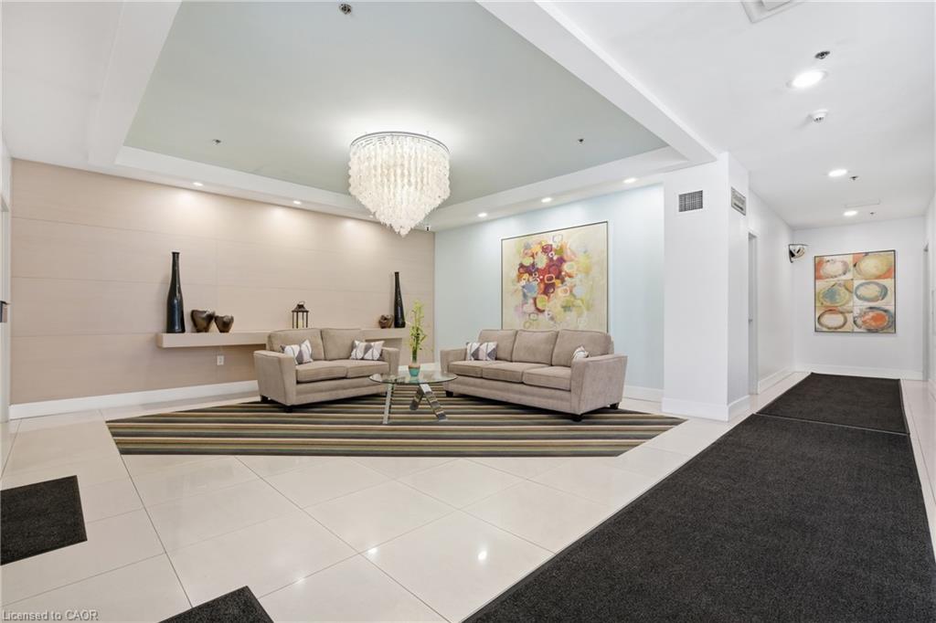 Recessed lighting illuminates a dropped ceiling with a crystal chandelier, complementing the large format tile flooring