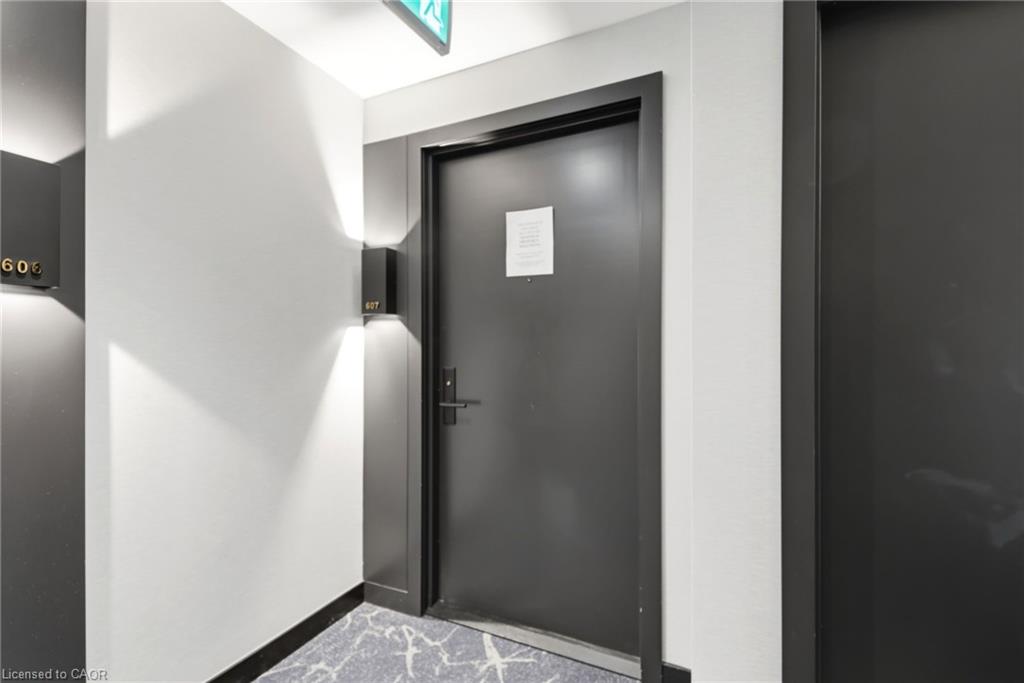 Modern entrance door with dark trim and hardware, set against a light-colored wall with contemporary wall-mounted lighting fixtures