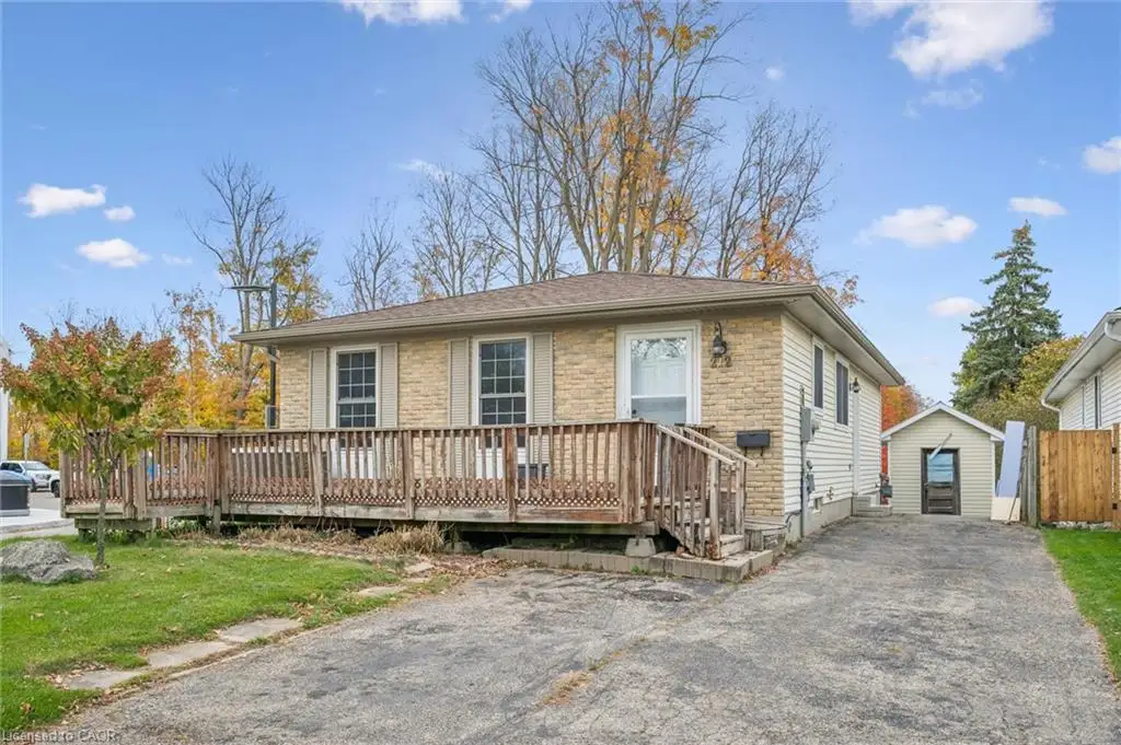 Stone-accented exterior with a sprawling wooden deck, attached single-car garage, and private driveway