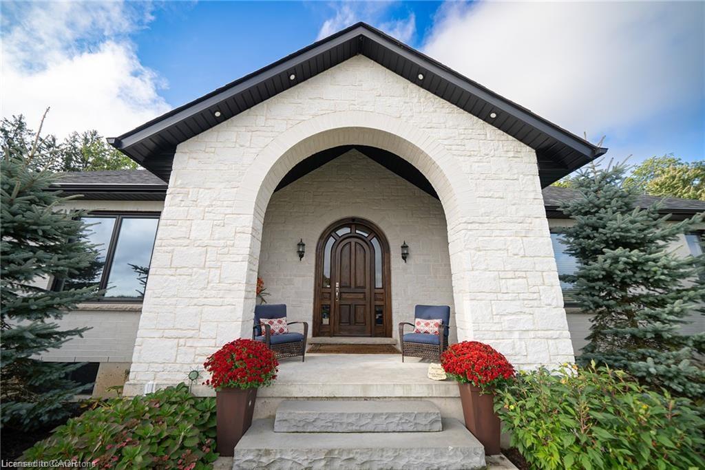 Arched stone entry featuring a solid wood door with decorative glass, stone steps, and dark trim details