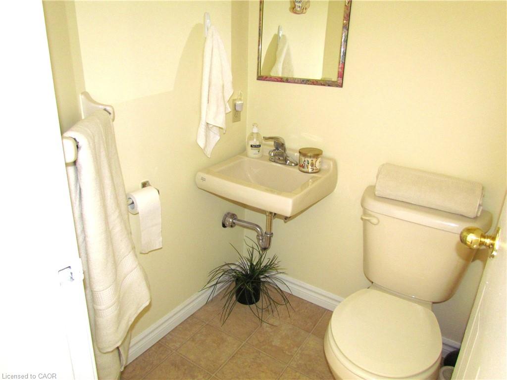 Compact powder room featuring a wall-mounted sink with chrome faucet, a standard toilet, and tiled flooring