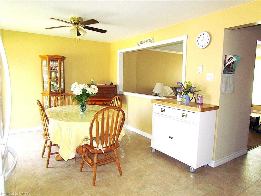 Dining area featuring light-toned flooring, a ceiling fan with integrated lighting, and a pass-through opening to an additional room