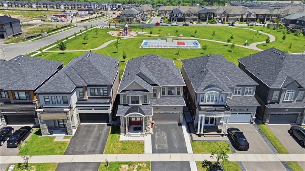 Modern residential architecture with a landscaped green space, paved walkways, a children's play area, and a sports court