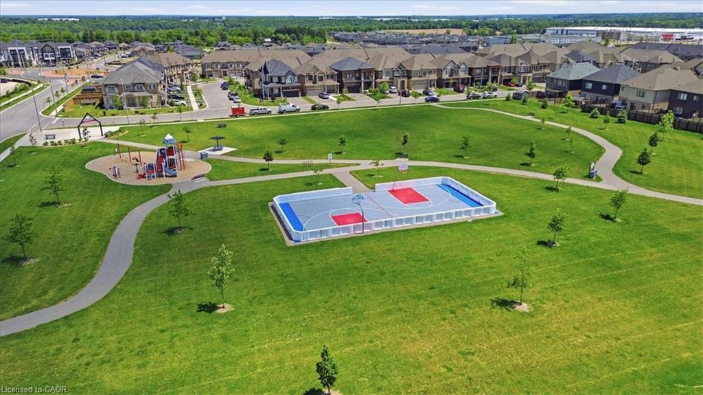 Expansive green space featuring paved walking paths, a dedicated play area, and a multi-sport court