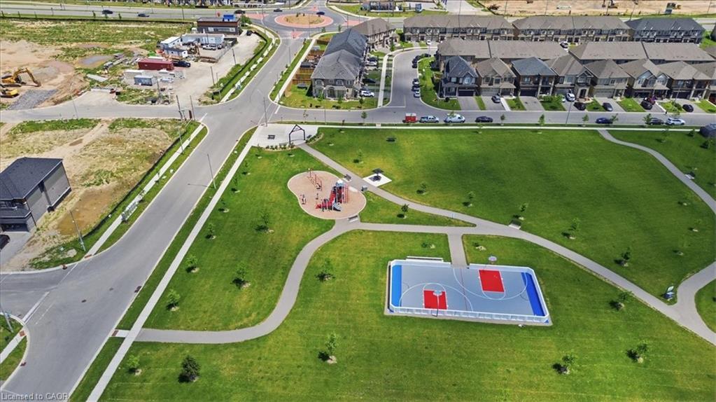 Expansive green space featuring walking paths, a playground structure, and a multi-sport court