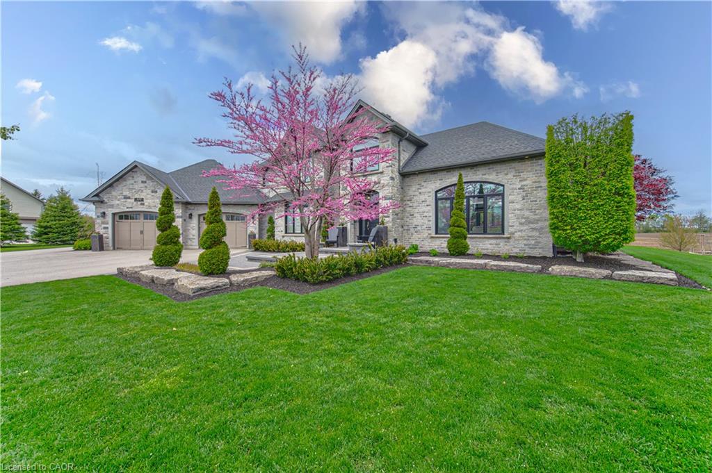 Stone exterior with arched windows, a dark shingle roof, and an attached two-car garage