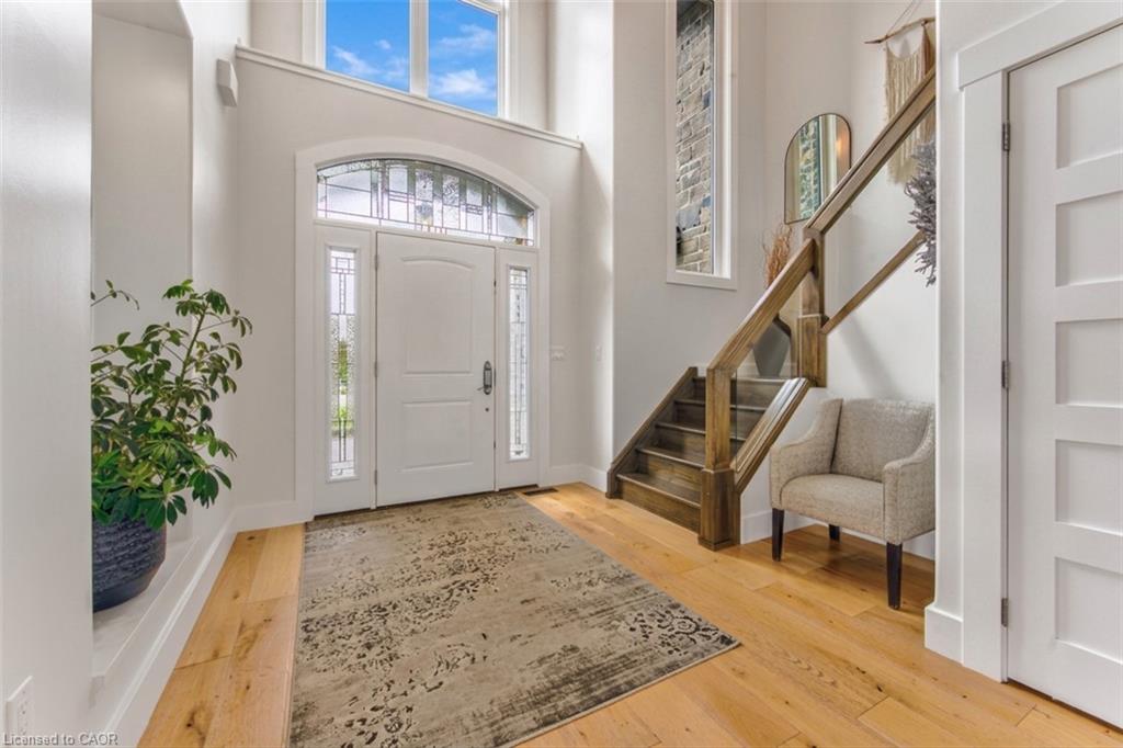 Hardwood flooring, arched transom window, leaded glass sidelights, wood staircase with railing, white paneled doors