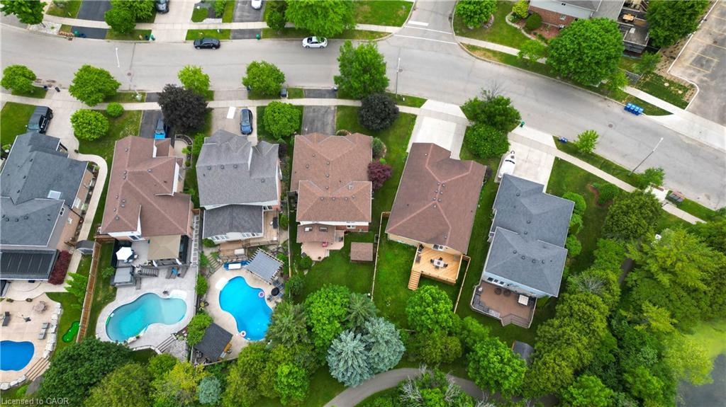 Aerial perspective showcasing a residential neighborhood with properties featuring varied rooflines, private swimming pools, and extensive green space