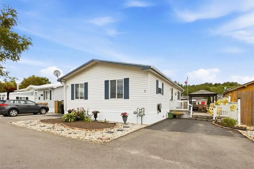 White horizontal siding exterior with dark shutters, paved driveway, landscaped garden bed, and rear patio with gazebo