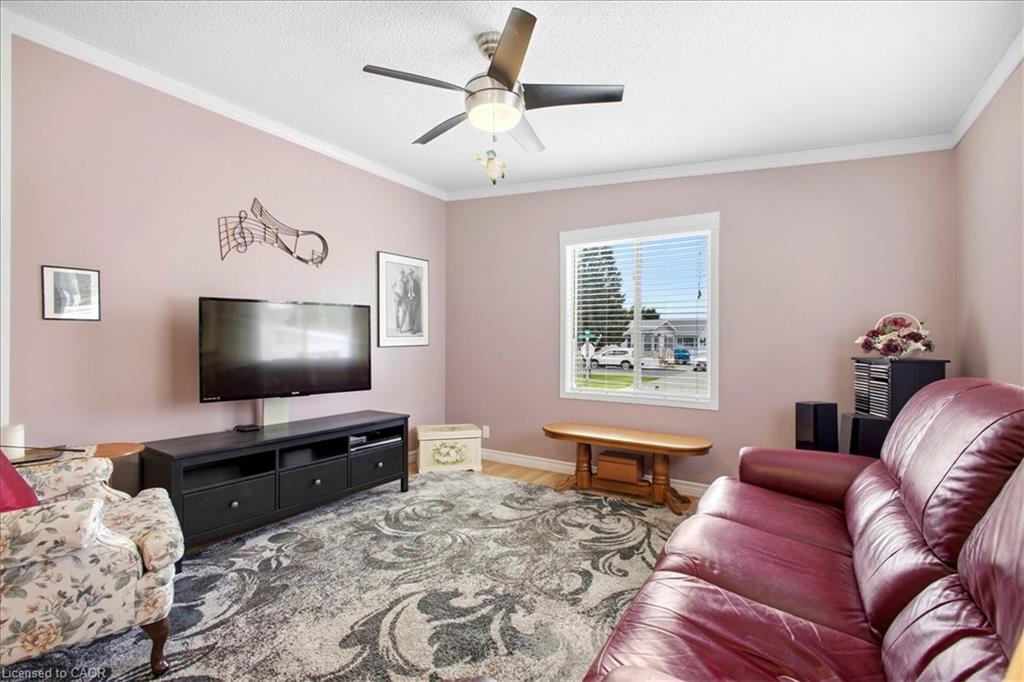 Crown molding detail, ceiling fan with integrated lighting, wood-finish flooring, and a window with horizontal blinds