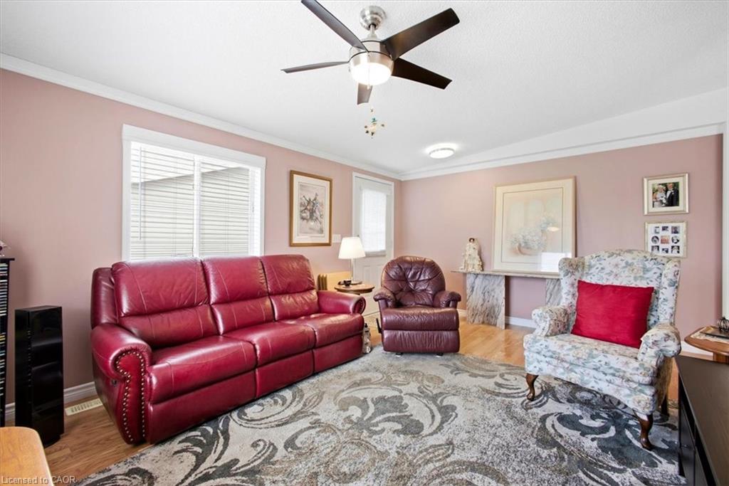 Recessed ceiling lights, crown molding, a ceiling fan with integrated lighting, wood-finish flooring, and a large window with horizontal blinds