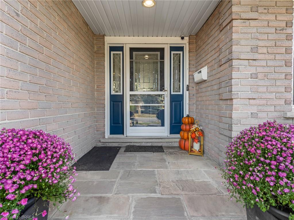Brick facade with a stone entry, featuring a blue front door with glass sidelights and an overhead soffit