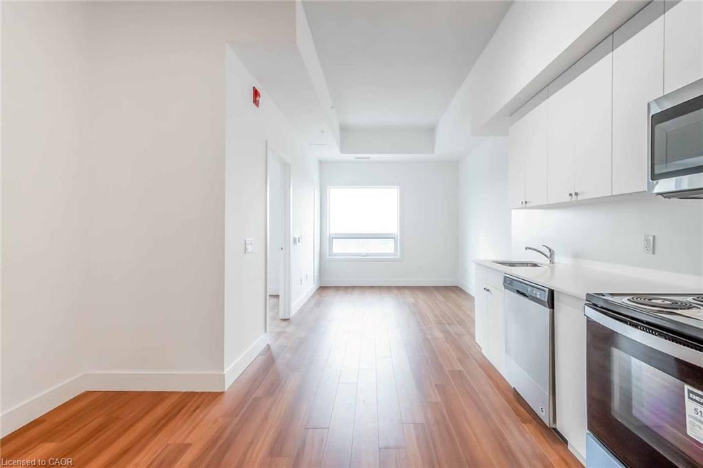Modern kitchen featuring white cabinetry, stainless steel appliances, and wood-finish flooring