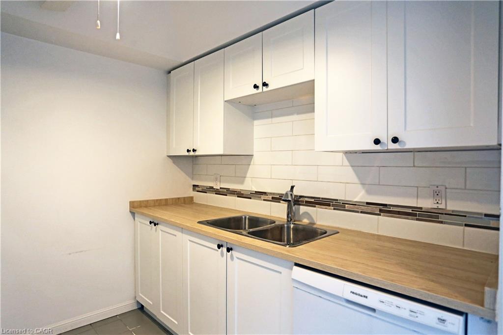 Kitchen with white dishwasher, white cabinetry, tasteful backsplash, and dark tile patterned flooring