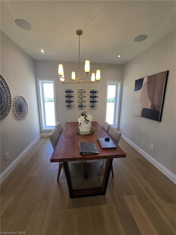 Dining area featuring light wood-finish flooring, recessed lighting, and a modern brass chandelier