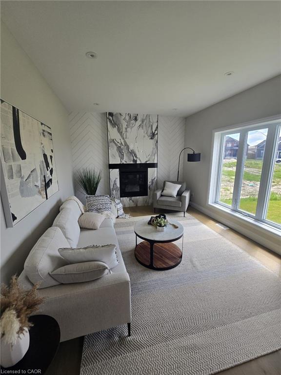 Living area featuring a modern fireplace with a marble-patterned surround, recessed lighting, expansive windows, light wood-finish flooring, and crisp white walls