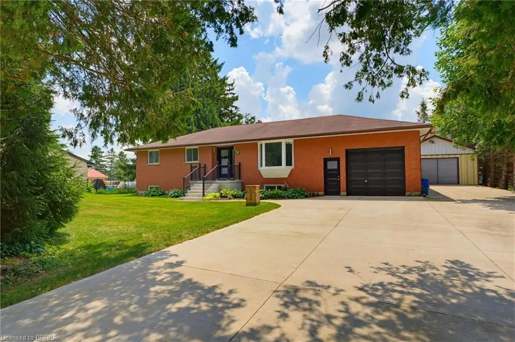 Red brick exterior featuring a multi-car concrete driveway, attached garage, and a separate detached garage structure