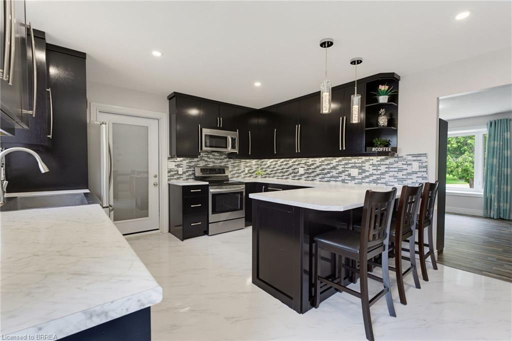 Modern kitchen with dark cabinetry, stainless steel appliances, and a mosaic tile backsplash