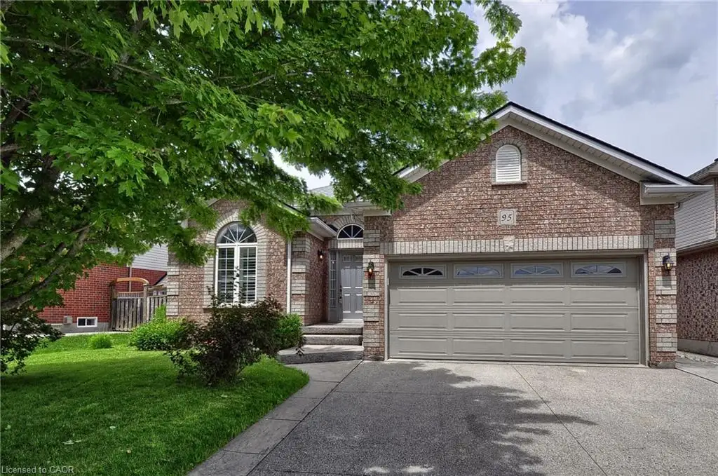 Brick exterior with a prominent arched window, a two-car garage, and a concrete driveway