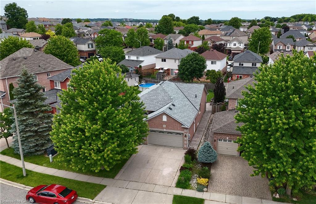 Brick exterior residence featuring a two-car garage, concrete driveway, and mature landscaping