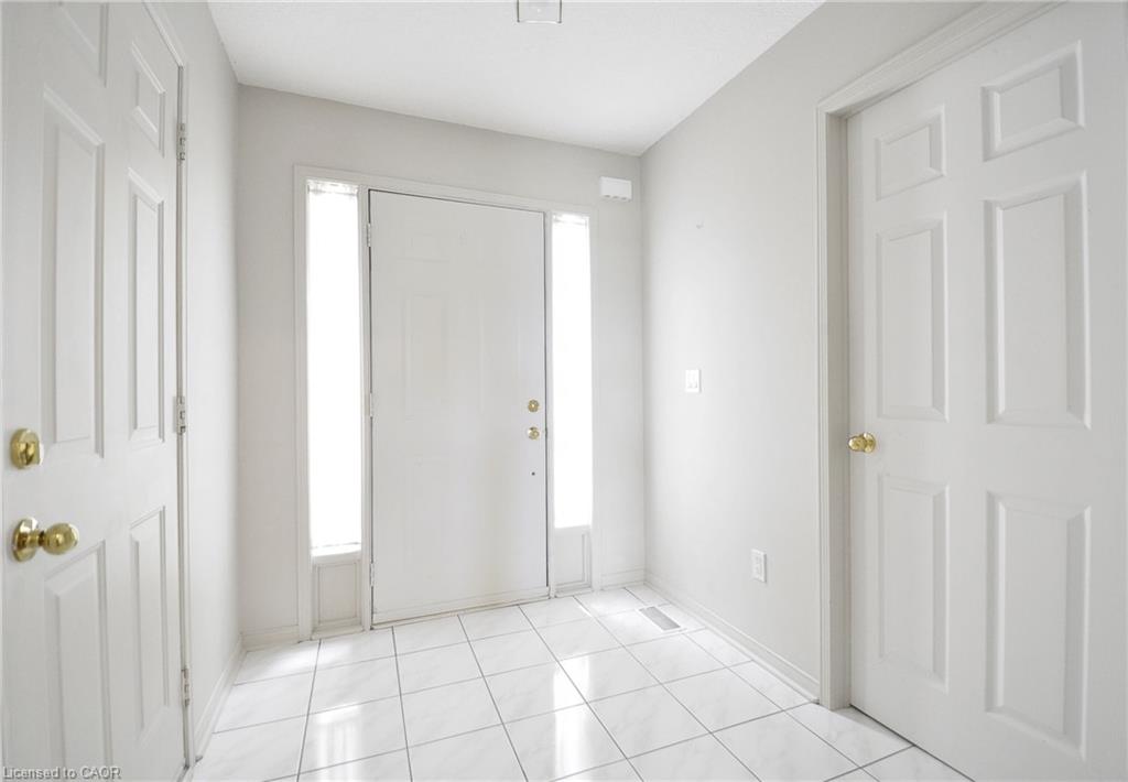 Entryway featuring white tile flooring and a solid white door with sidelight windows