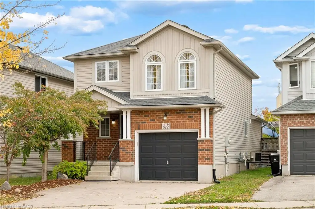 Two-story residence featuring a brick and siding exterior, arched upper-level windows, a single-car garage, and a front entry staircase with iron railings