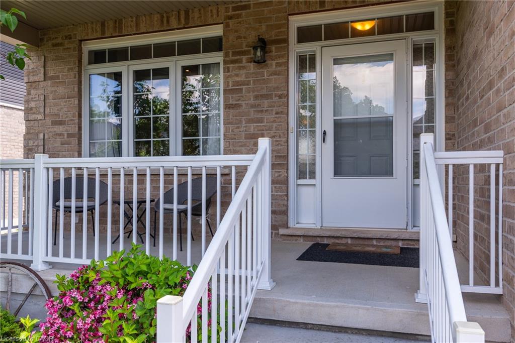 Inviting front porch featuring a white railing system, brick exterior, and a prominent entry door with sidelights and transom window