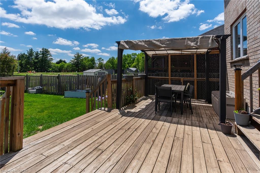Wood-finish deck featuring a covered pergola, lattice privacy screen, and direct access to a fenced backyard with a manicured lawn