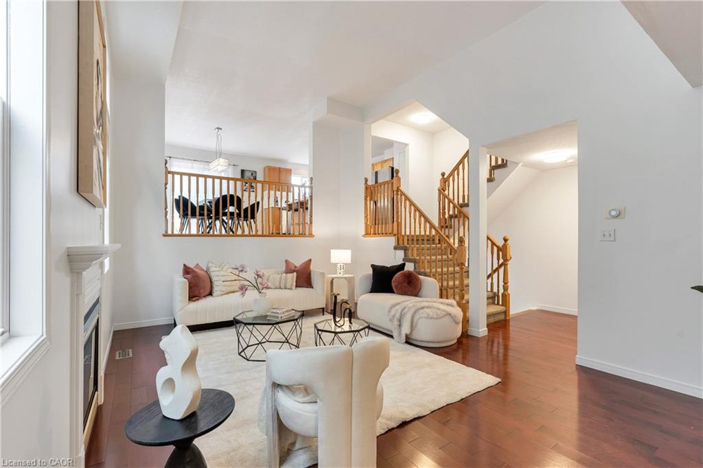 Hardwood flooring throughout, a white fireplace with mantle, and a wooden staircase with balusters