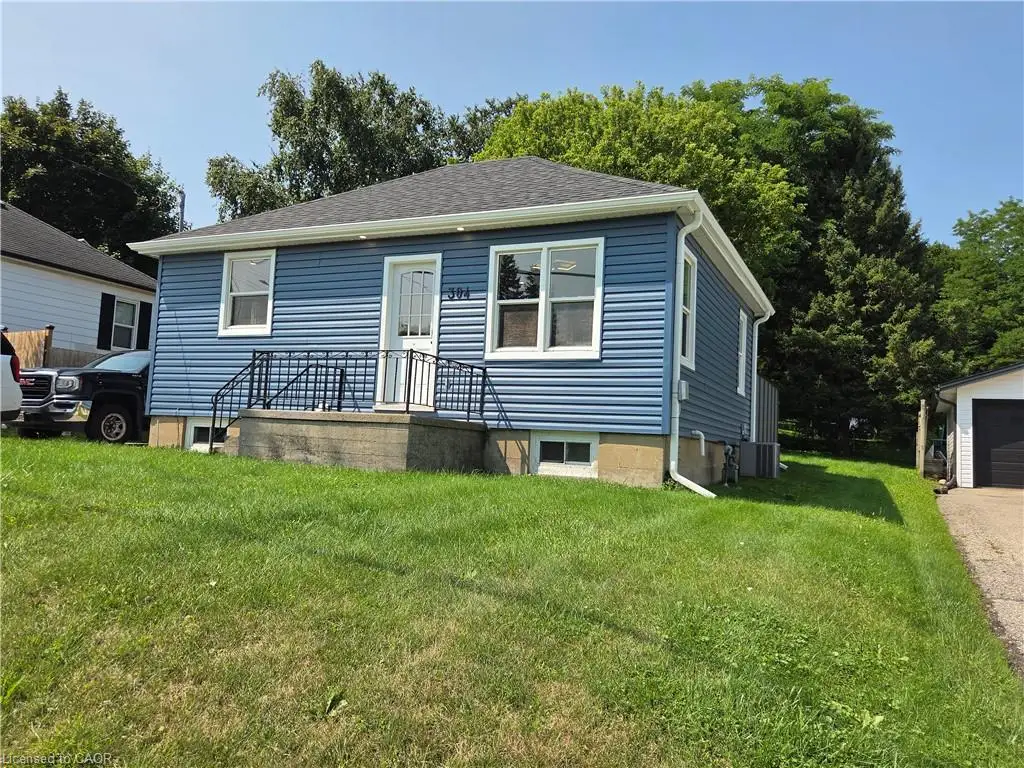 Blue horizontal siding, white trim, white front entry door, black metal handrails, and a detached garage