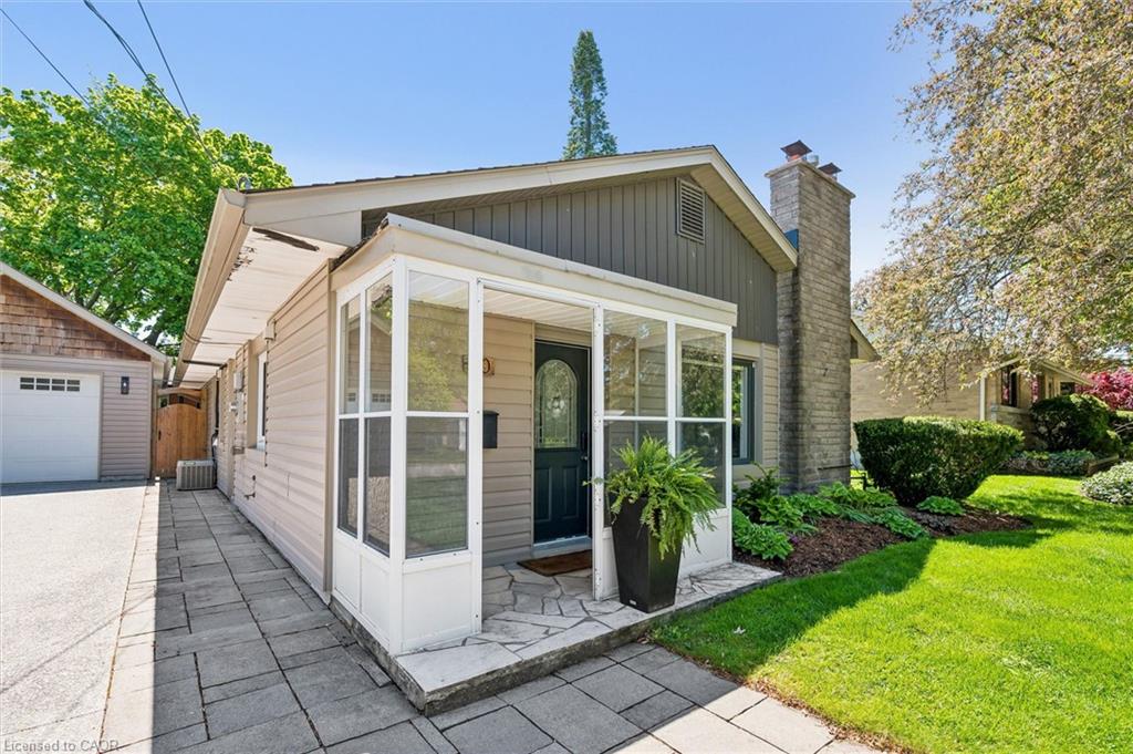 Enclosed front porch with stone step, stone chimney, and an attached garage with shaker siding