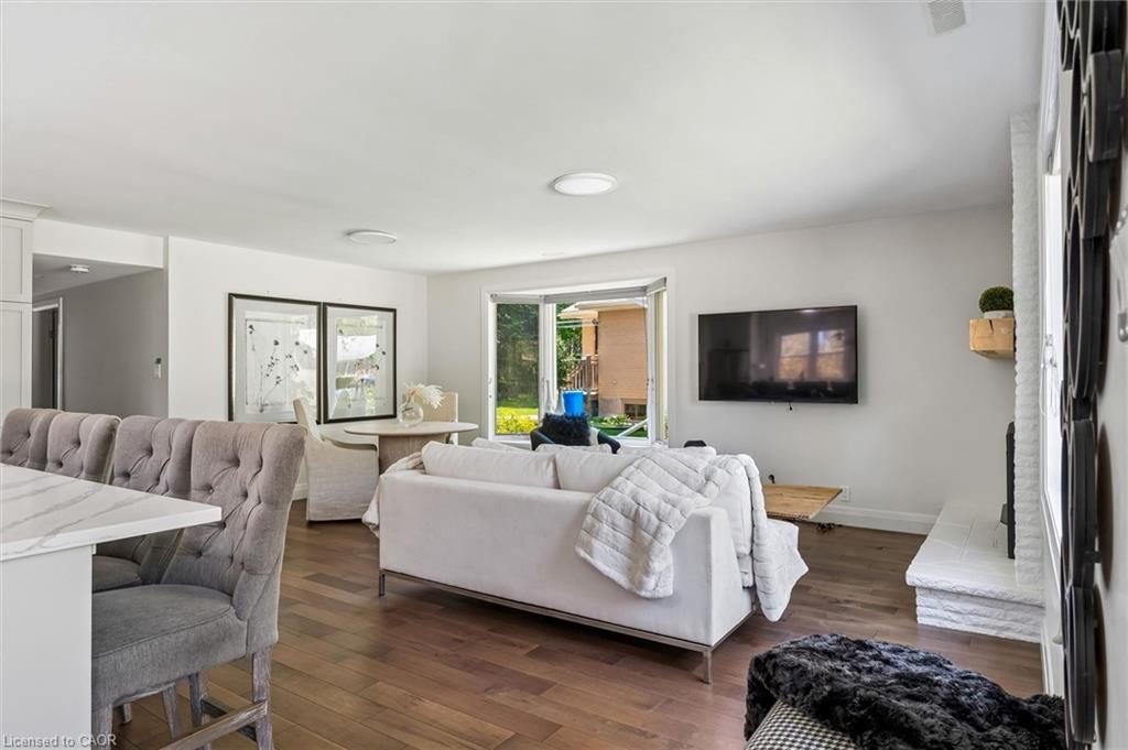Open-concept living area featuring warm wood-finish flooring, recessed ceiling lighting, and large glass sliding doors opening to outdoor space