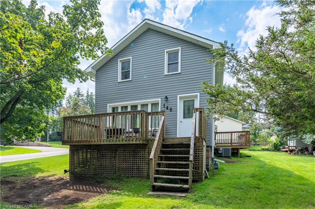 Gable-roof home featuring horizontal siding, a multi-level wood deck with lattice skirting, and mature trees on a grassy lot