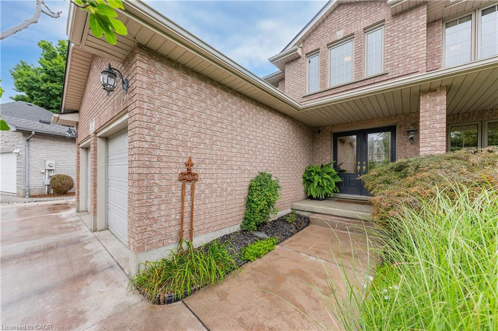 Brick exterior with two-car garage, covered entry, double entry doors, and landscaping