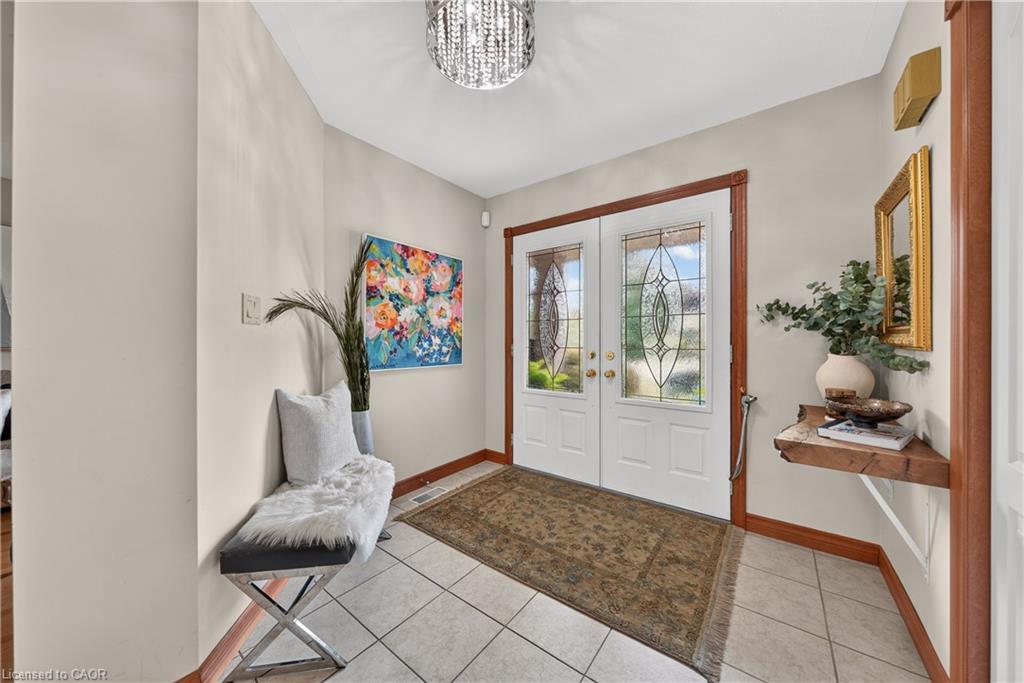 Double entry doors with decorative glass panels, tile flooring, and wood trim accents