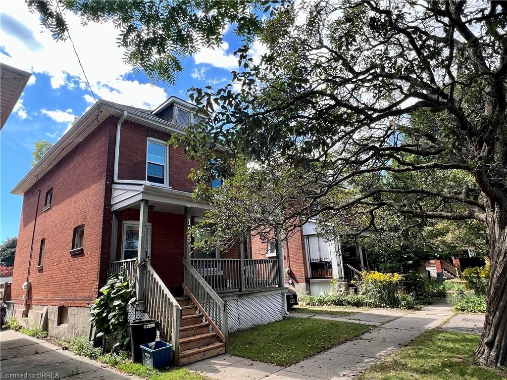Red brick exterior with white trim, a covered porch, and exterior stairs