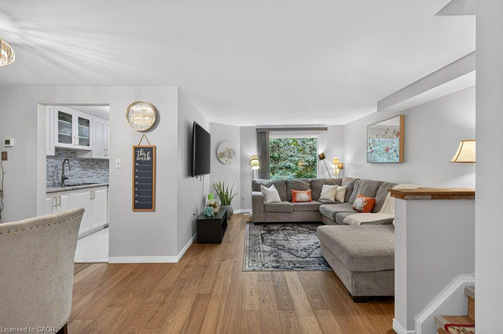 Hardwood-finish flooring, recessed window, white cabinetry, tile backsplash, and built-in wall lighting