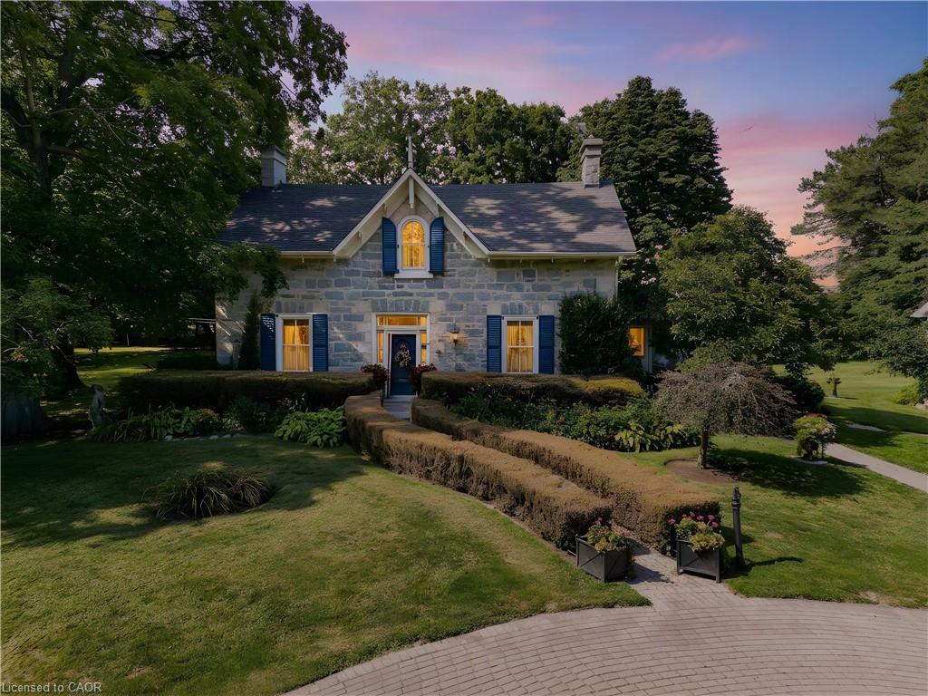 Stone facade residence with a gabled roofline, blue shutters, and a prominent chimney