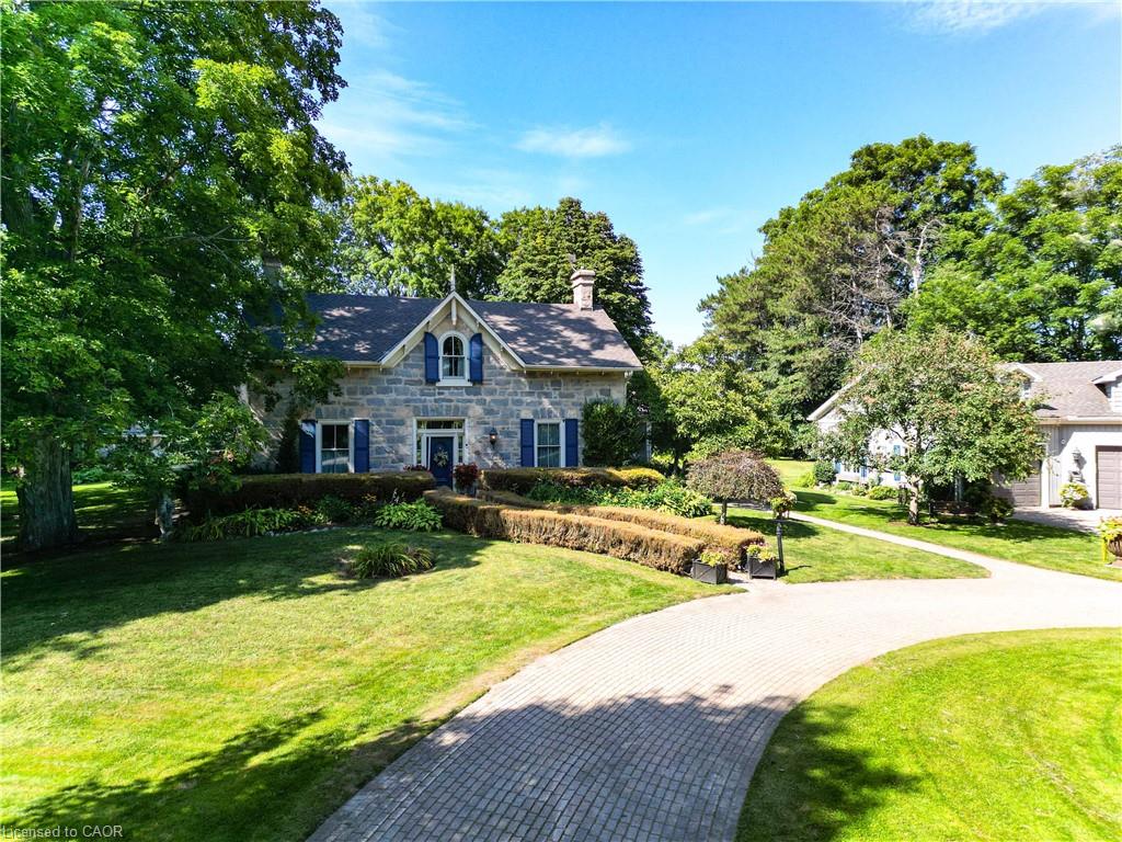 Stone exterior residence featuring blue window shutters, a prominent front chimney, and a paved circular driveway