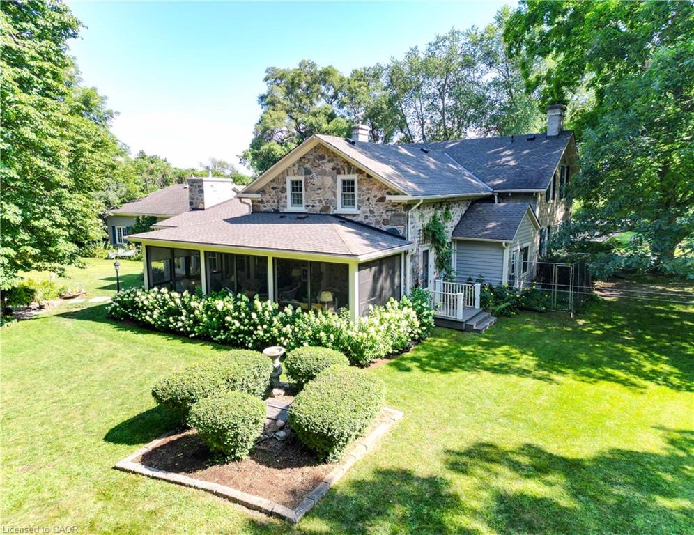 Stone and siding exterior with a screened porch, multiple chimneys, and a deck