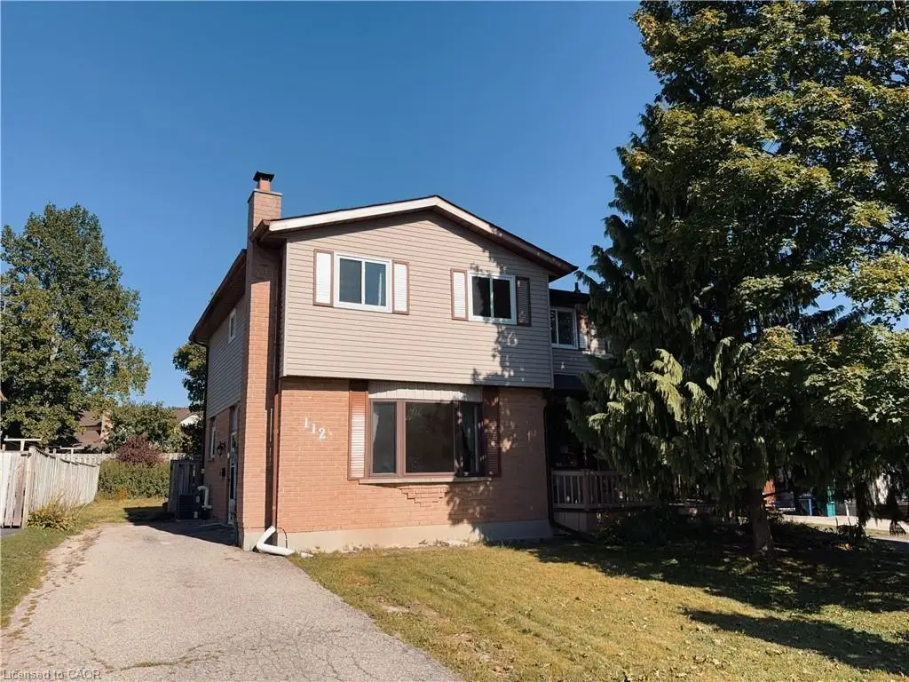 Two-story residence featuring brick and siding exterior, front yard with mature trees, and a paved driveway