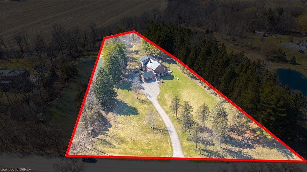 Aerial view of property and surrounding area featuring property boundaries highlighted and a heavily wooded area
