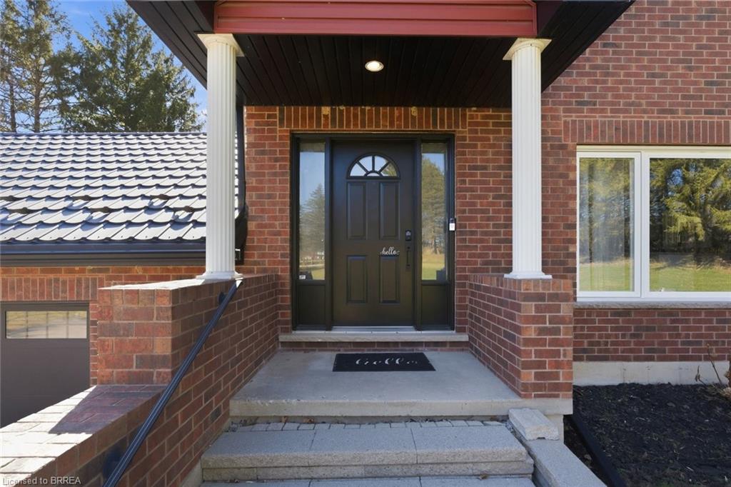 Entrance to property featuring covered porch and brick siding