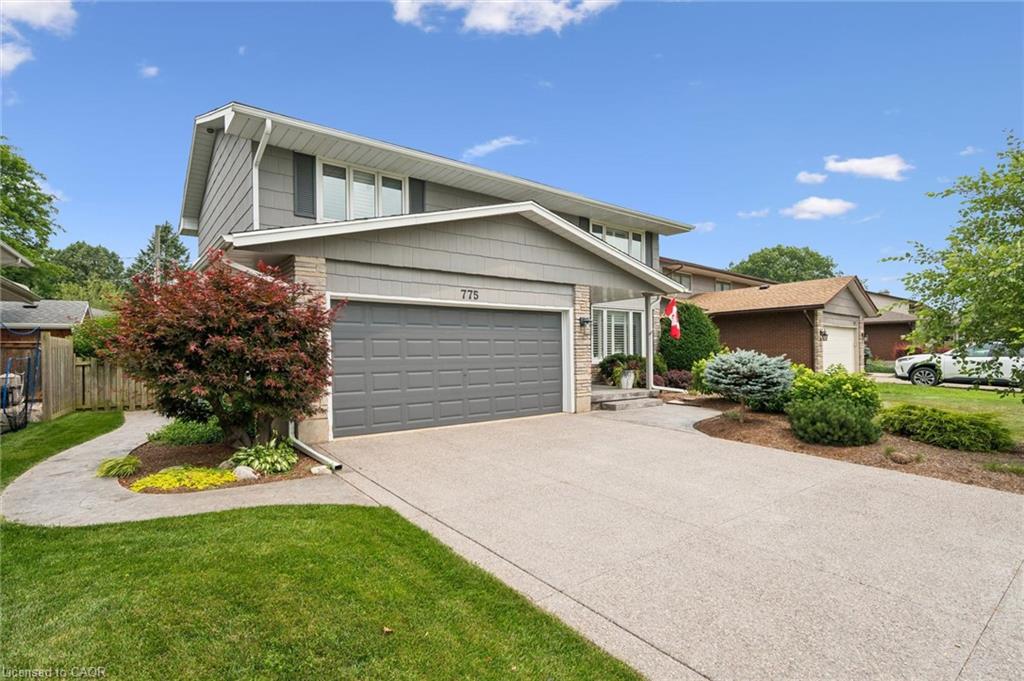 Exterior featuring grey siding, a two-car garage with a panel door, stone accents, and a concrete driveway
