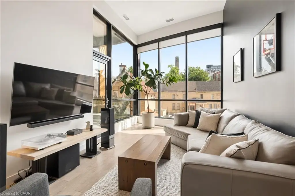 Living area featuring expansive floor-to-ceiling windows, light wood-finish flooring, and a textured area rug