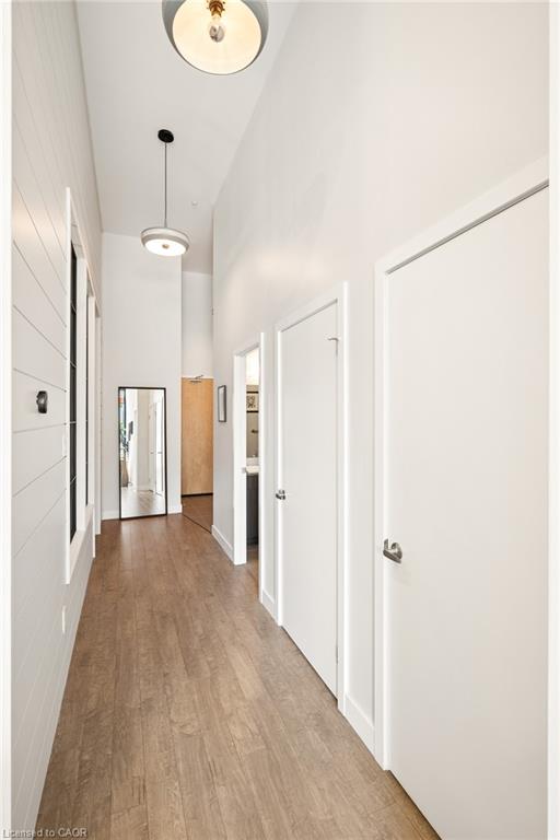 Hallway featuring wood-finish flooring, white shiplap accent wall, white painted walls, and contemporary ceiling light fixtures