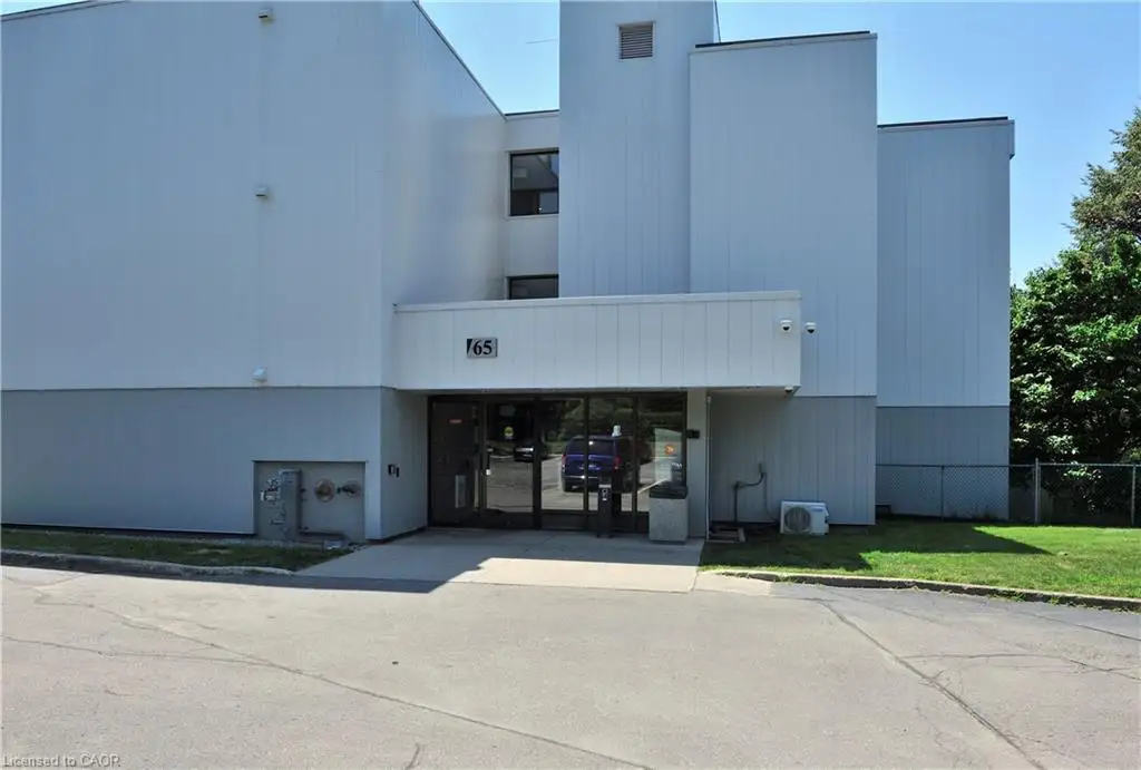 Multi-story building featuring a prominent entrance with glass doors, a white facade with vertical paneling, and a light gray lower exterior
