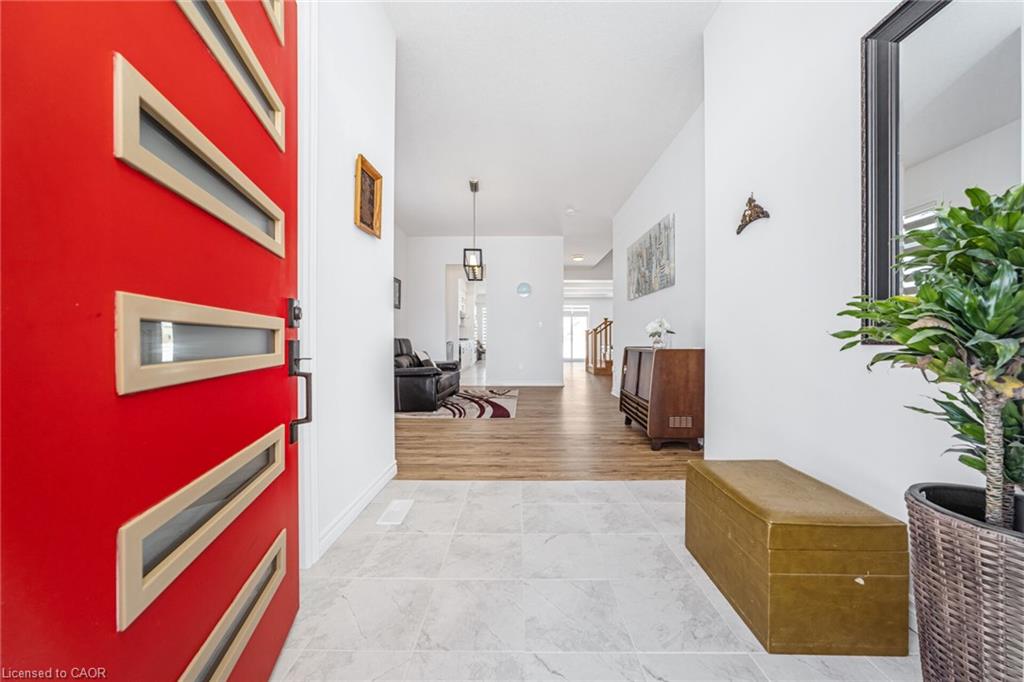 Red entry door with multiple horizontal glass inserts, tile flooring in the entry, and wood-finish flooring extending into the interior