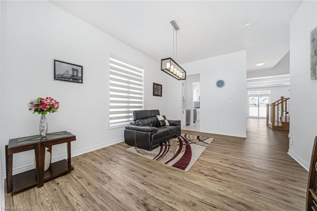 Wood-finish flooring throughout, white walls, and a contemporary linear chandelier