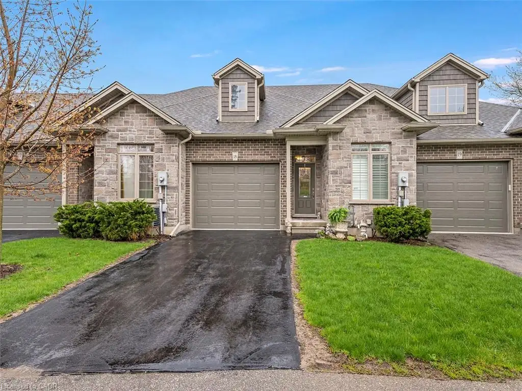 Stone and brick facade featuring an attached garage, a dormer window, and asphalt driveway
